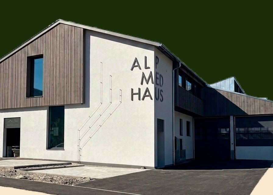 Das Alpmed Haus in Götzens: heller Neubau mit Holzfassade und dem Schriftzug ALPMED HAUS.